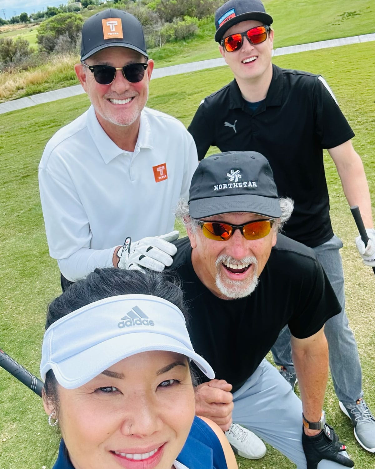 Four Teter employees posing together on a golf course, smiling widely with their clubs.