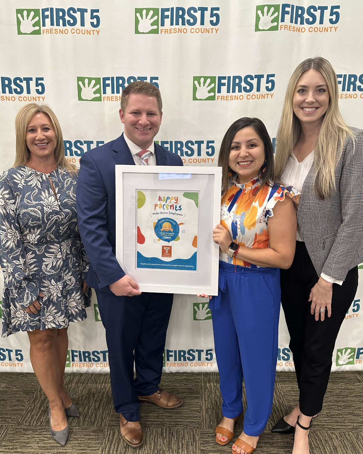 Four Teter employees holding a framed recognition award, standing in front of a First5 Fresno County backdrop.