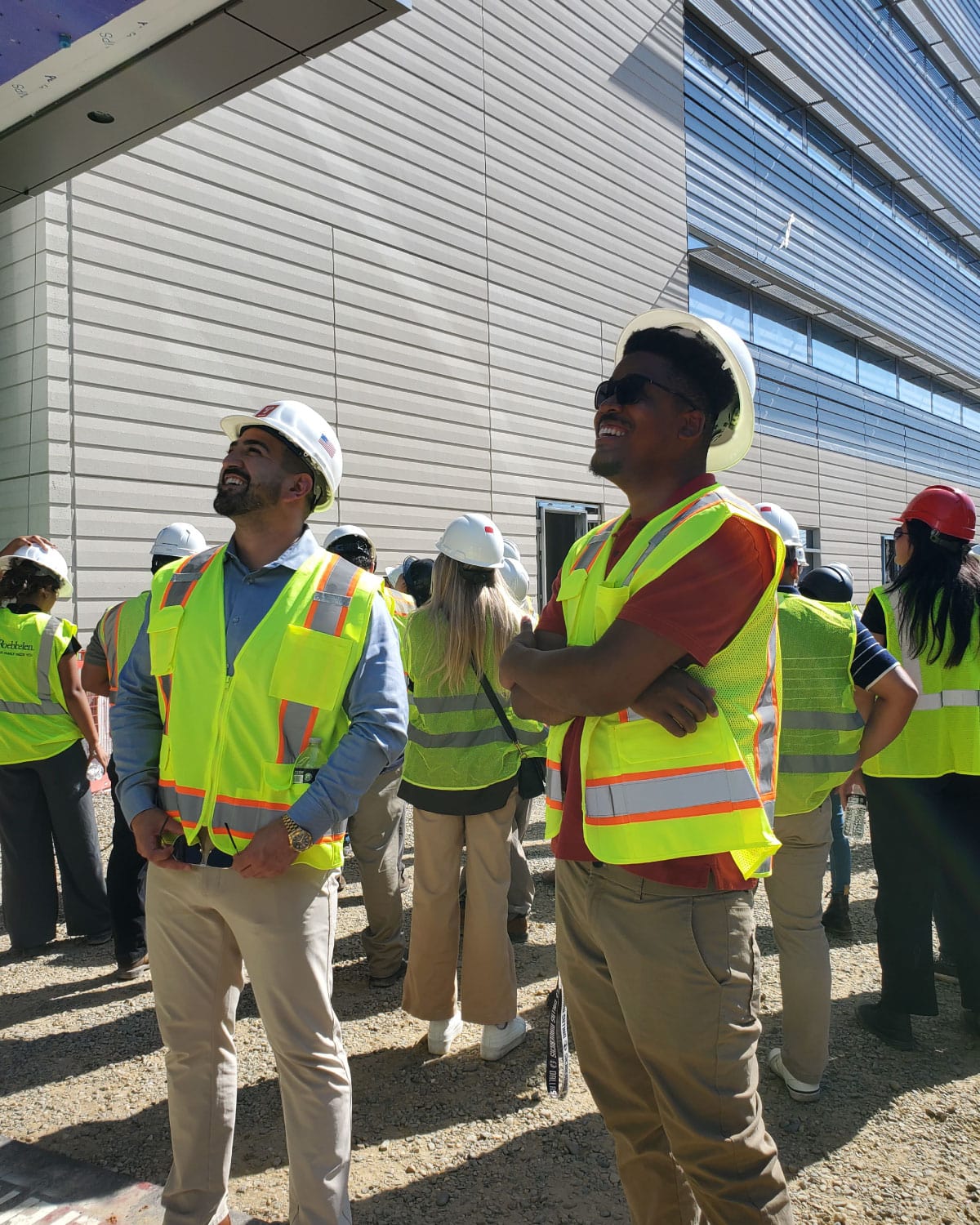 Teter employees wearing hard hats and safety vests, looking up and observing details at a construction site.