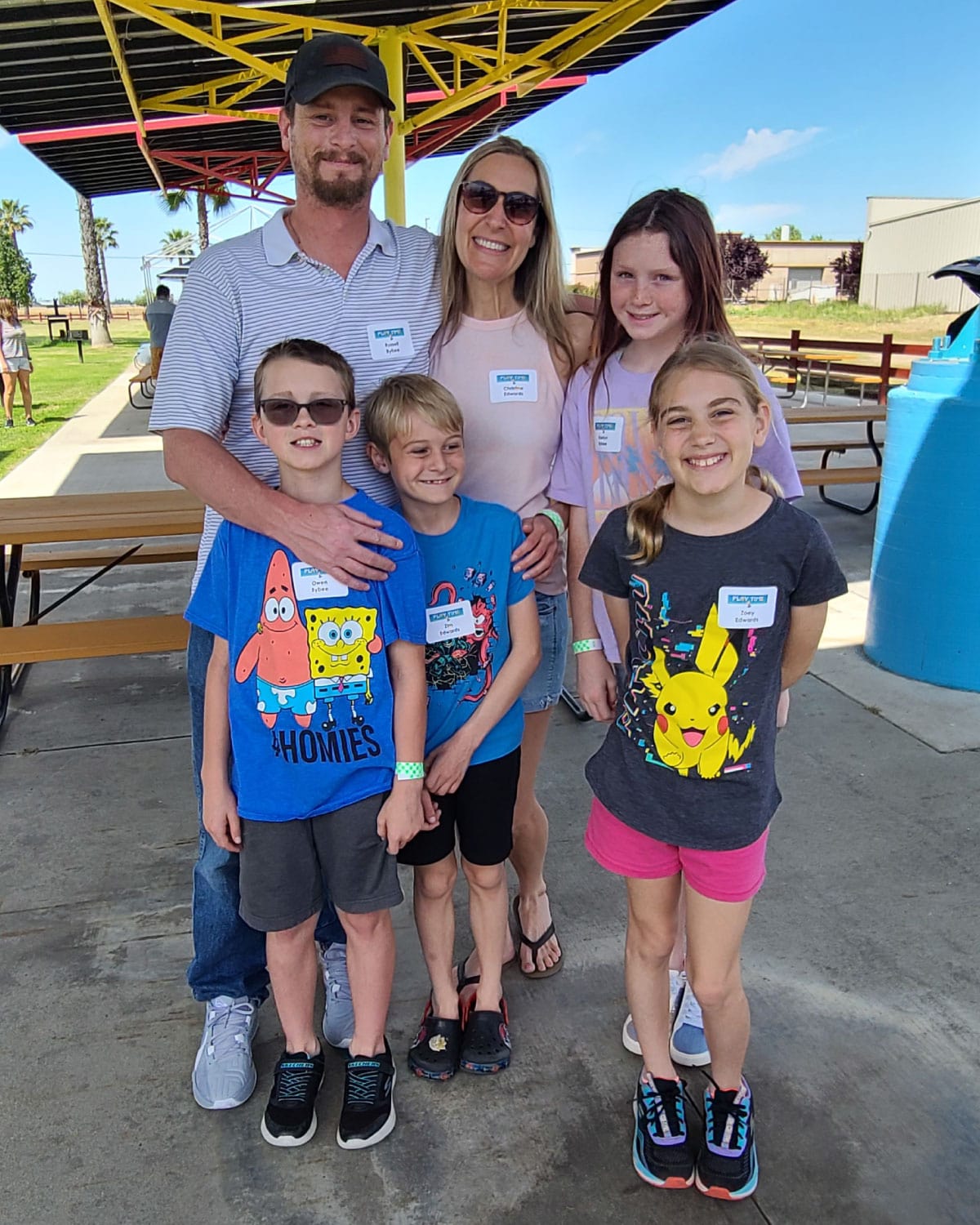 A Teter employee and their family of five, smiling together under a bright shelter at an outdoor event.