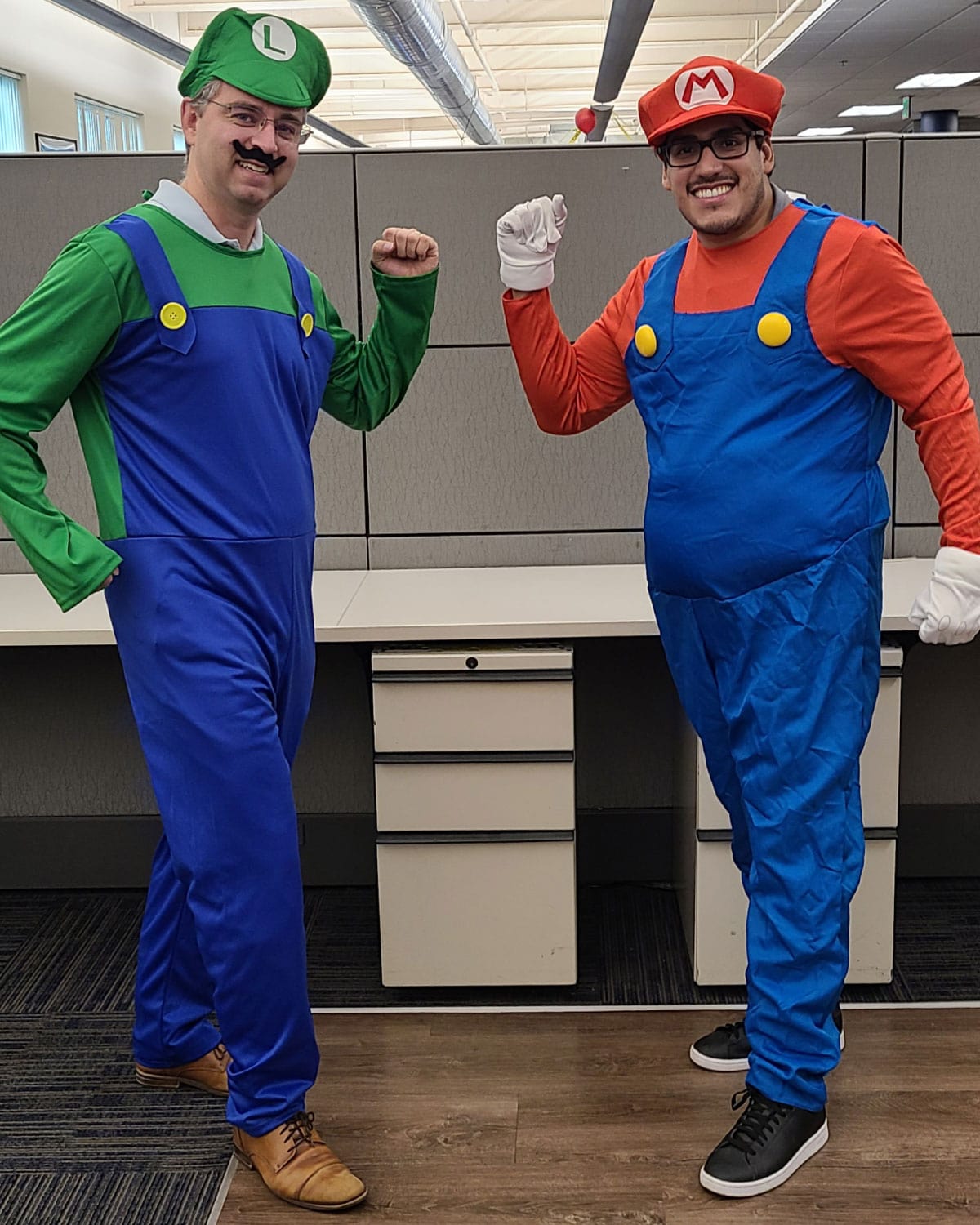 Two Teter employees dressed as Mario and Luigi, striking a fun, celebratory pose in their office.