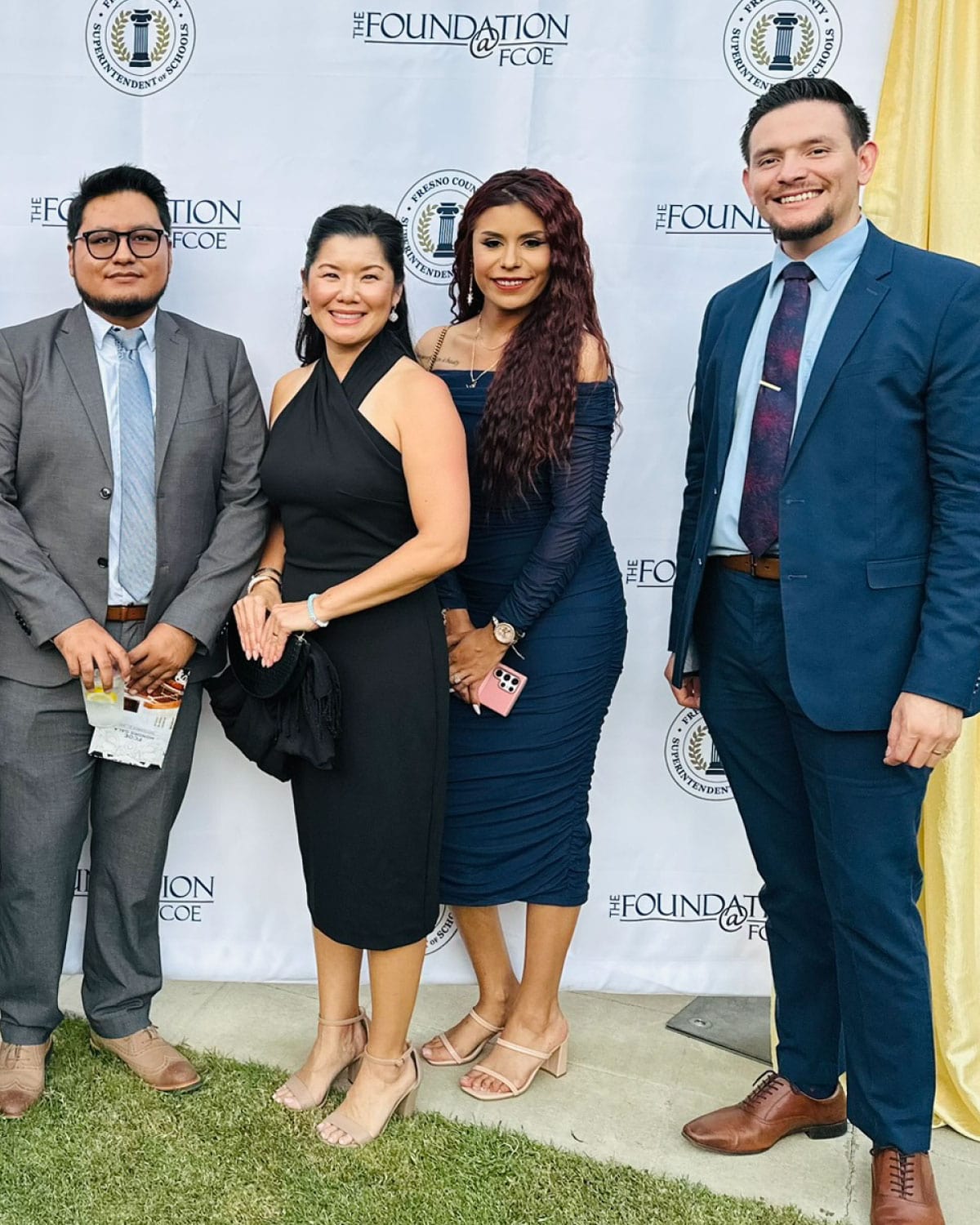 Four Teter employees dressed elegantly, smiling at an outdoor event in front of a ‘The Foundation at FCOE’ backdrop.